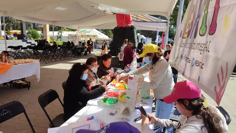 Personas conversando en una mesa de atención en una feria comunitaria