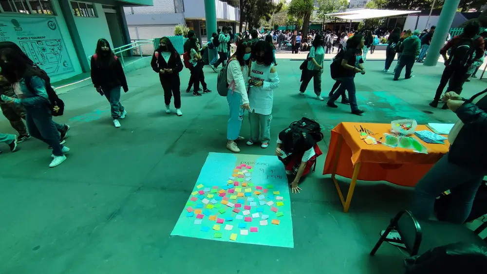 Jóvenes participando en una dinámica con notas de colores en el patio de una escuela